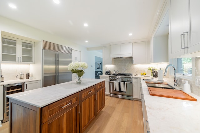 kitchen featuring high quality appliances, wine cooler, a center island, backsplash, and recessed lighting