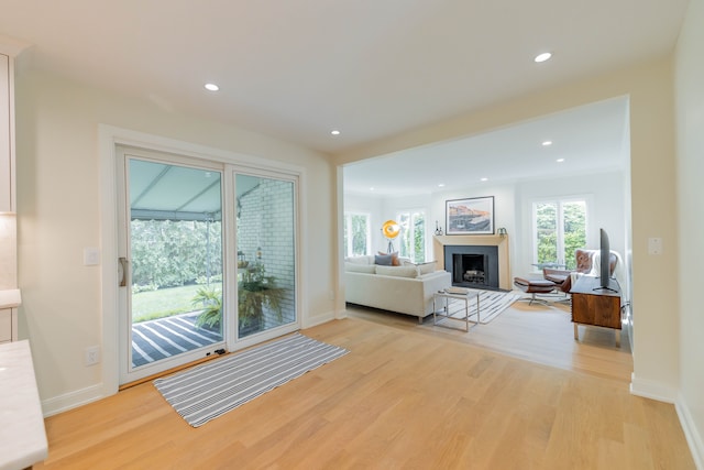 living area featuring light wood finished floors, a fireplace, recessed lighting, and baseboards