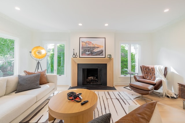 living room with plenty of natural light, recessed lighting, crown molding, a fireplace with flush hearth, and wood finished floors