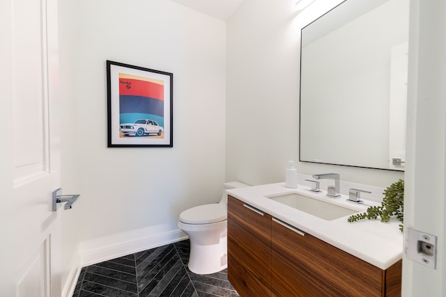 bathroom with toilet, baseboards, and vanity