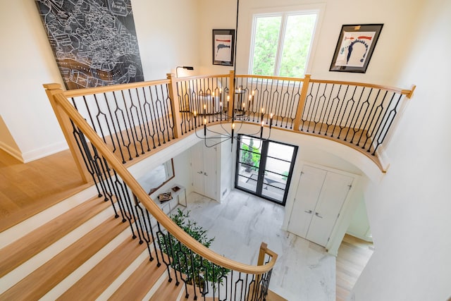 stairway featuring a chandelier, a high ceiling, and wood finished floors
