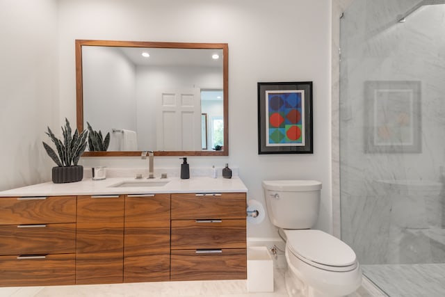 bathroom featuring toilet, a marble finish shower, vanity, and baseboards