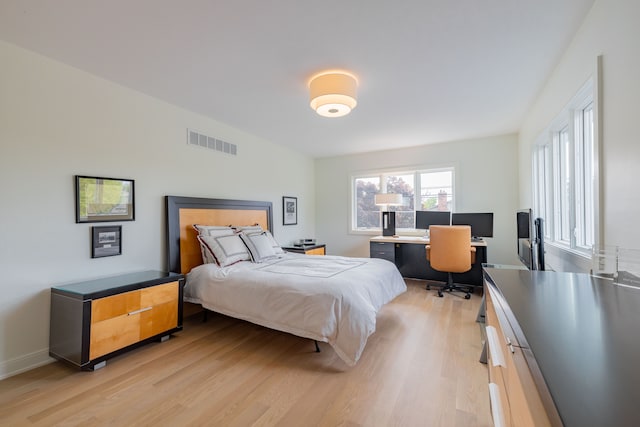 bedroom with light wood-style flooring, an office area, and baseboards