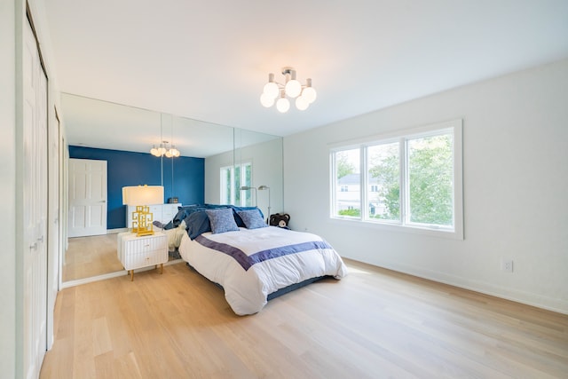bedroom with a chandelier, light wood-style floors, and baseboards