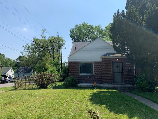 bungalow-style house featuring fence, a front lawn, and brick siding