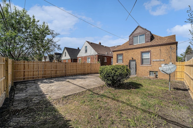 rear view of house featuring brick siding, a fenced backyard, and a patio area
