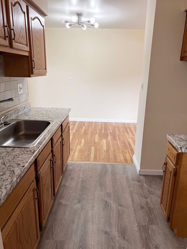 25954 Salem Unit 5, Roseville, MI 48066 - kitchen with baseboards, brown cabinets, tasteful backsplash, a sink, and light wood-style flooring