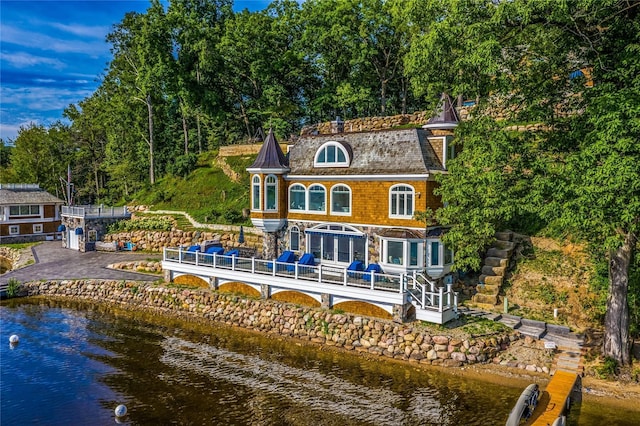 rear view of house with stairs and a deck with water view
