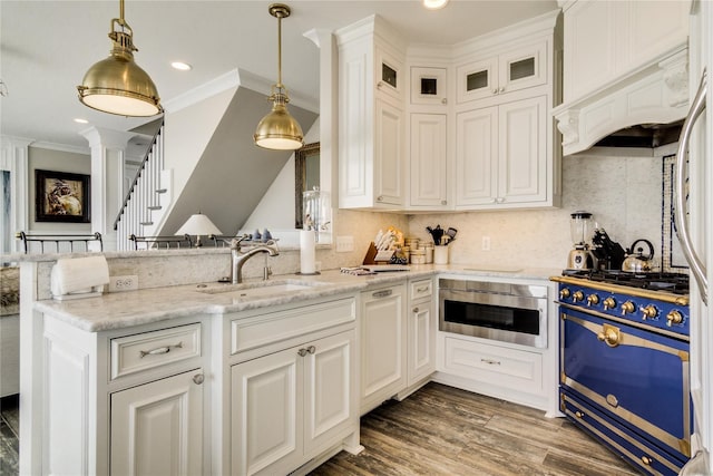 kitchen featuring pendant lighting, decorative backsplash, a peninsula, a sink, and stainless steel appliances