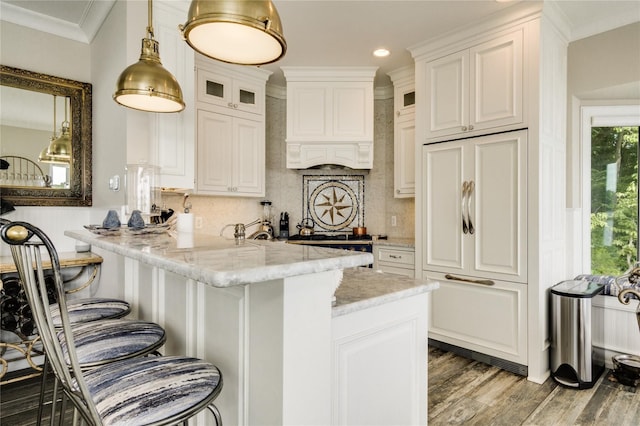 kitchen featuring custom exhaust hood, glass insert cabinets, tasteful backsplash, and a kitchen bar