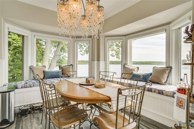sunroom / solarium with a water view, a notable chandelier, and wood finished floors