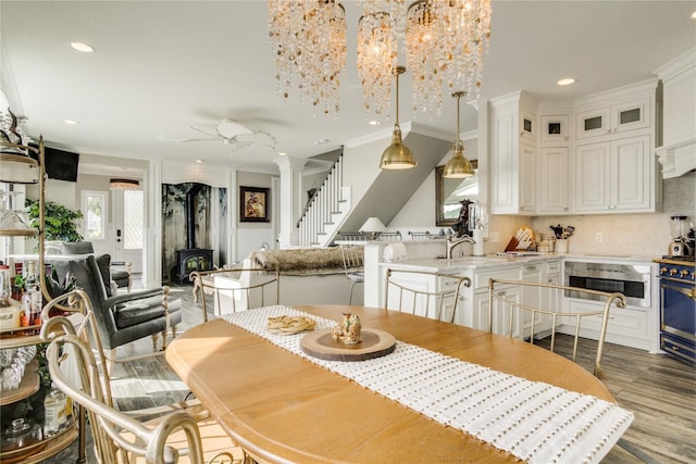 dining room with recessed lighting, a wood stove, wood finished floors, and ornamental molding
