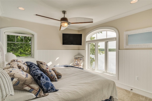 bedroom featuring carpet flooring, ceiling fan, and a wainscoted wall