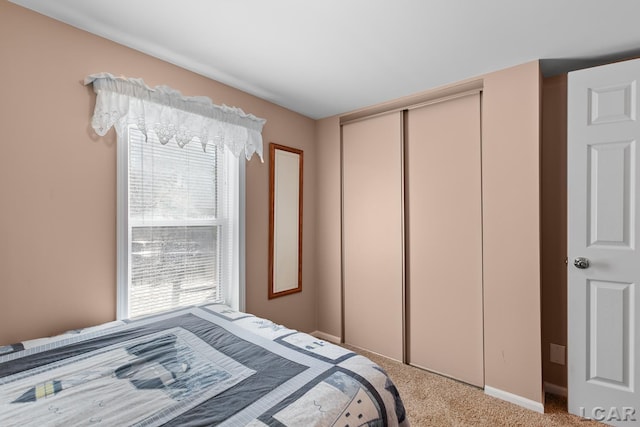 bedroom featuring carpet floors, multiple windows, baseboards, and a closet