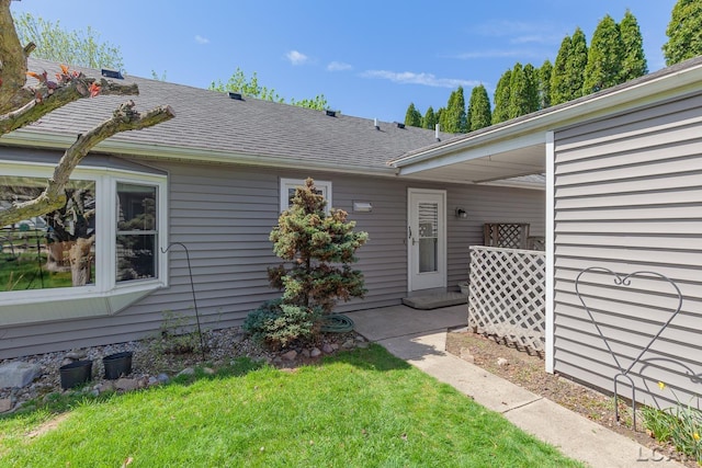 doorway to property with a lawn and roof with shingles