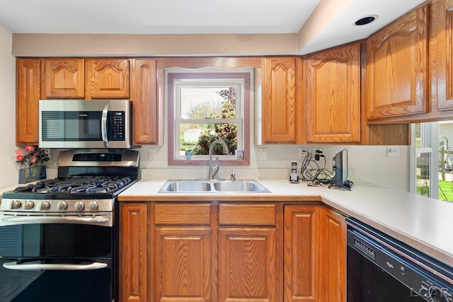 kitchen with light countertops, appliances with stainless steel finishes, a healthy amount of sunlight, and a sink