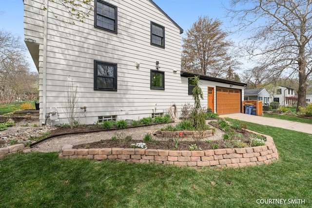 view of side of home featuring a lawn, driveway, and a garage