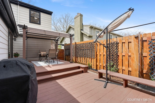 wooden terrace with fence, a pergola, outdoor dining area, and a grill