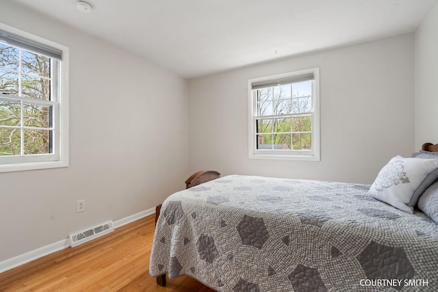 bedroom with baseboards, wood finished floors, and visible vents