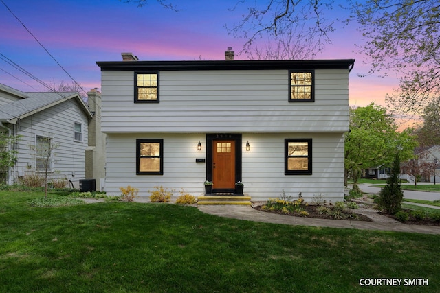 colonial home featuring a lawn, a chimney, and central AC unit