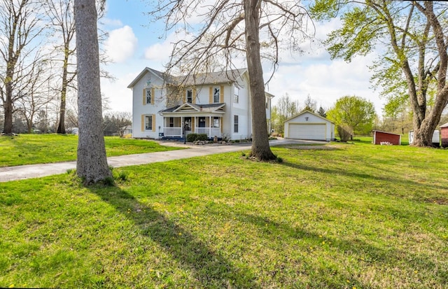 traditional-style home with covered porch, driveway, a front yard, an outbuilding, and a detached garage