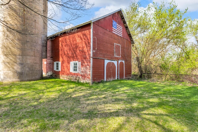 view of barn featuring a lawn and fence