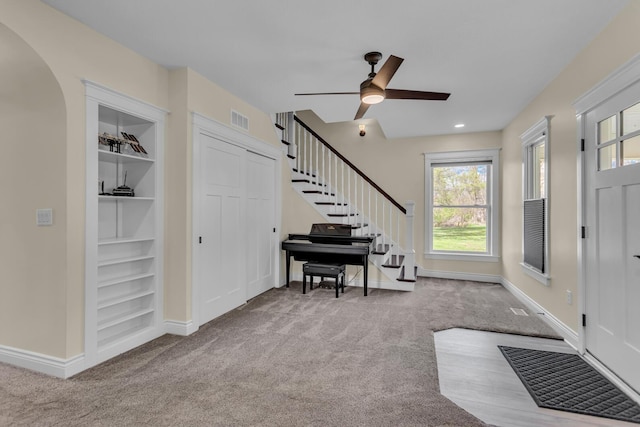 entrance foyer featuring carpet floors, a ceiling fan, visible vents, and a wealth of natural light