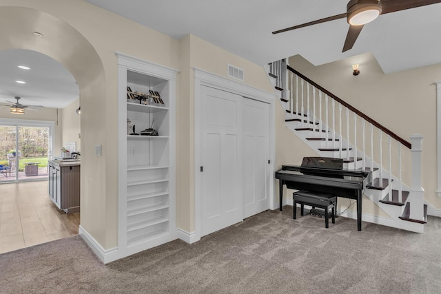 interior space with carpet floors, a ceiling fan, visible vents, and stairway