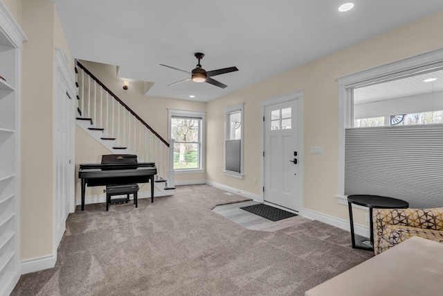 carpeted foyer entrance with baseboards, a ceiling fan, and stairs
