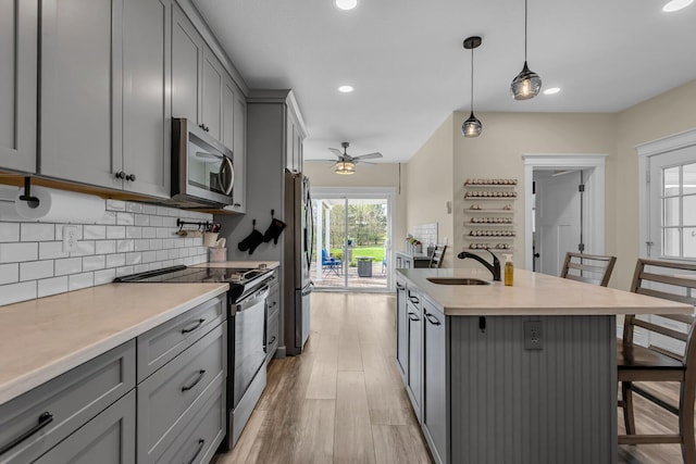kitchen featuring a sink, a kitchen bar, gray cabinetry, and stainless steel appliances