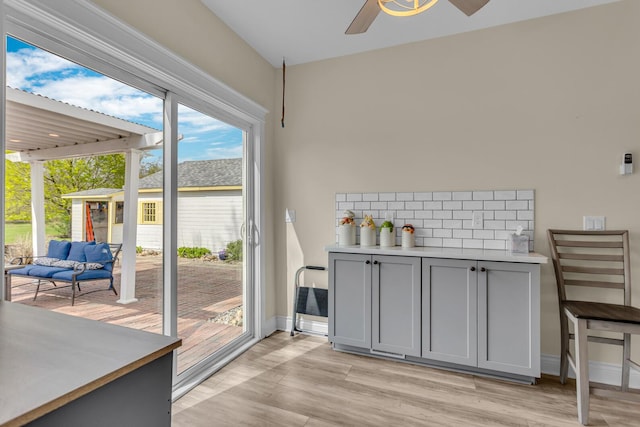 doorway to outside with ceiling fan, baseboards, and light wood finished floors