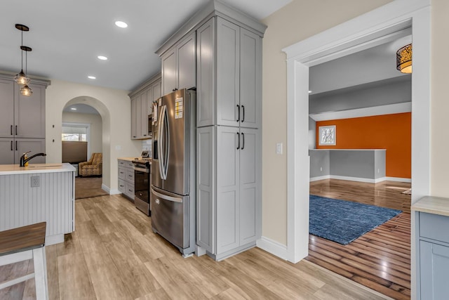 kitchen featuring baseboards, a sink, appliances with stainless steel finishes, and light wood-type flooring