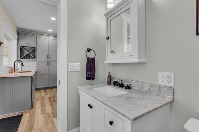 bathroom with wood finished floors, a sink, and two vanities