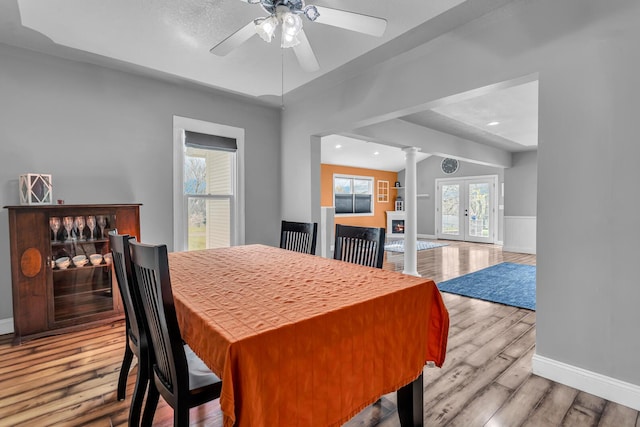 dining area with ceiling fan, french doors, decorative columns, wood finished floors, and baseboards