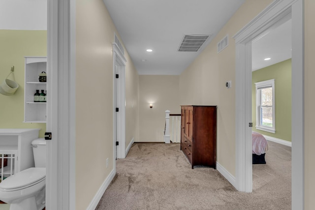 hall featuring visible vents, carpet flooring, baseboards, and an upstairs landing