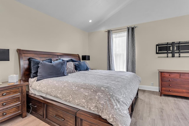 bedroom with baseboards, vaulted ceiling, and light wood-type flooring