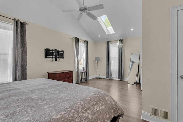 bedroom featuring vaulted ceiling with skylight, visible vents, wood finished floors, baseboards, and recessed lighting