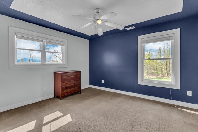 spare room with a healthy amount of sunlight, baseboards, ceiling fan, and carpet