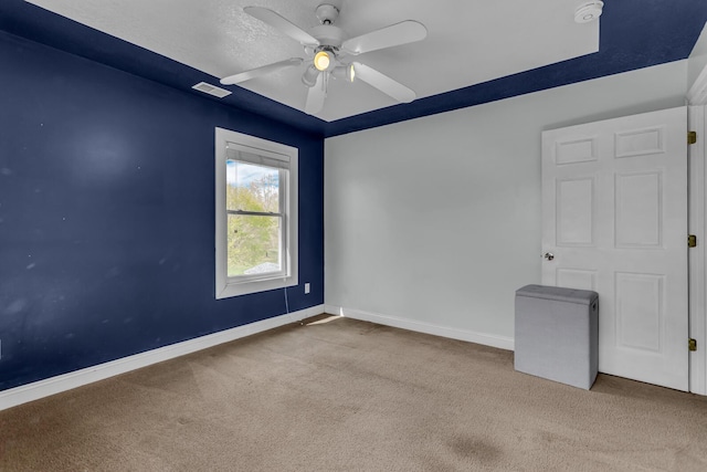 carpeted spare room with baseboards, ceiling fan, and visible vents