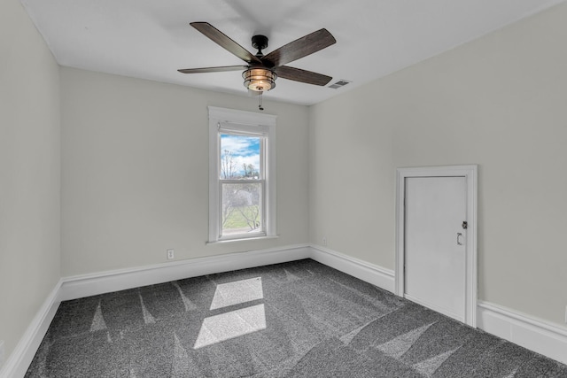 empty room featuring baseboards, a ceiling fan, dark carpet, and visible vents