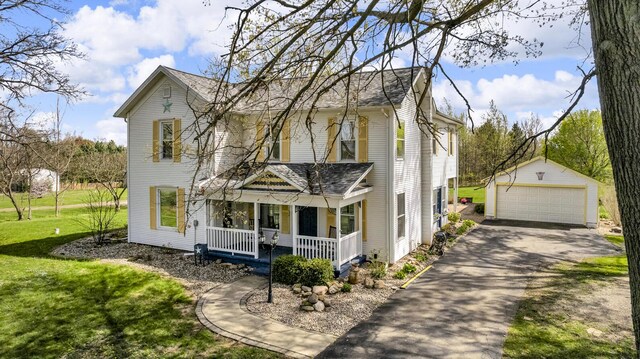 view of front of property featuring a porch, an outbuilding, a detached garage, a front lawn, and a shingled roof