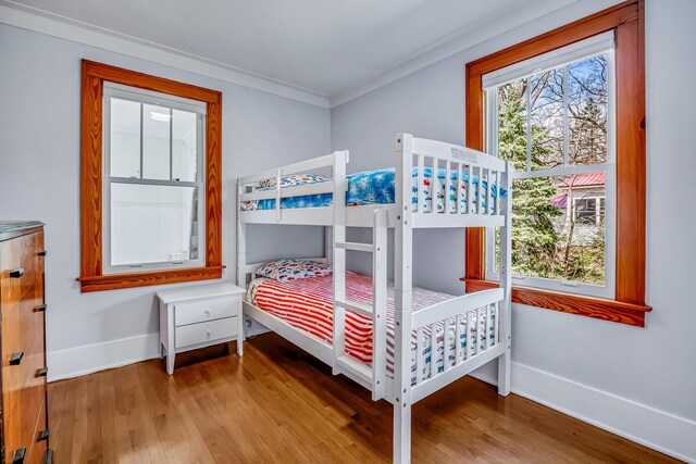 bedroom with baseboards, ornamental molding, and wood finished floors