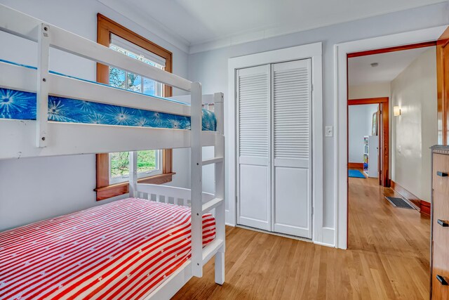 bedroom featuring baseboards, a closet, light wood finished floors, and visible vents