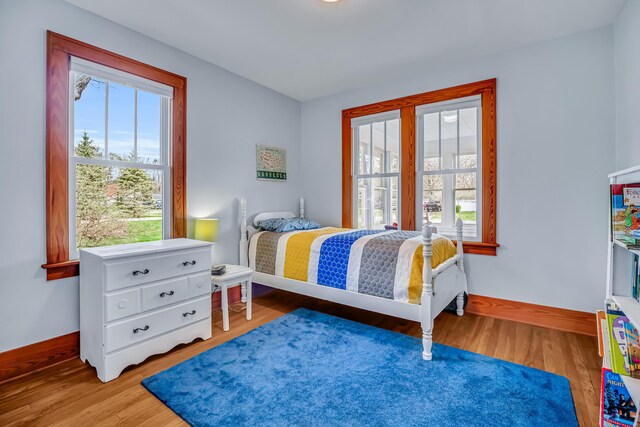 bedroom featuring baseboards, wood finished floors, and multiple windows