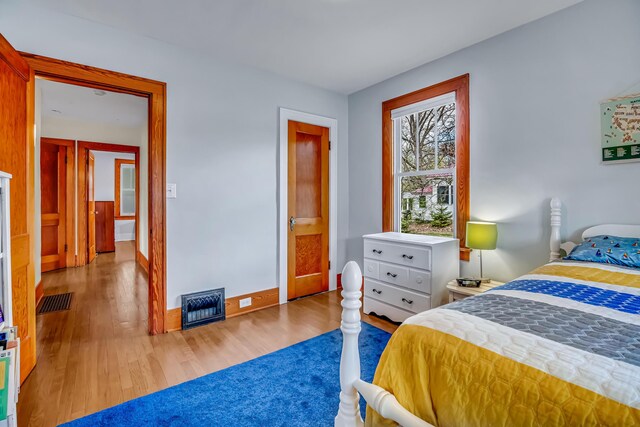 bedroom with baseboards, wood finished floors, and visible vents