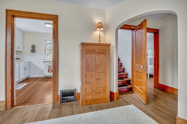 interior space with visible vents, wood finished floors, baseboards, stairway, and arched walkways