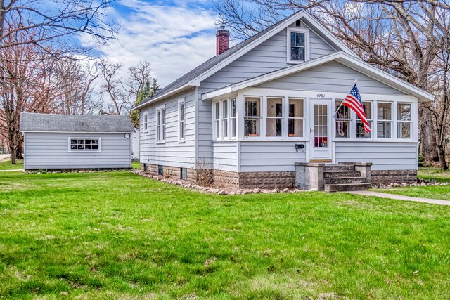 bungalow with a sunroom, a chimney, and a front yard