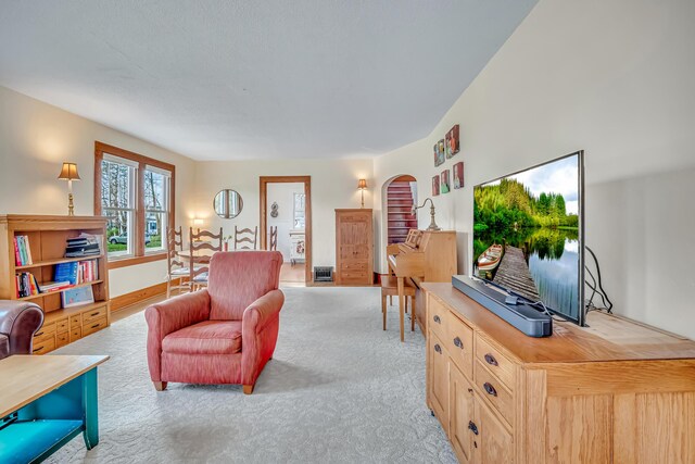 living room with arched walkways and light colored carpet