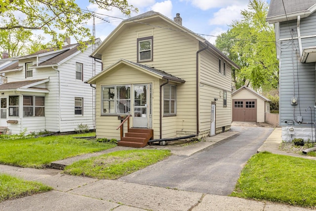 1319 Rhodes St, Jackson, MI 49202 - view of front facade with entry steps, an outdoor structure, asphalt driveway, a detached garage, and a chimney