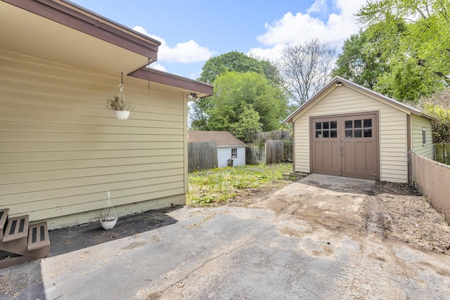 1319 Rhodes St, Jackson, MI 49202 - view of patio featuring a shed, fence, a detached garage, driveway, and an outdoor structure